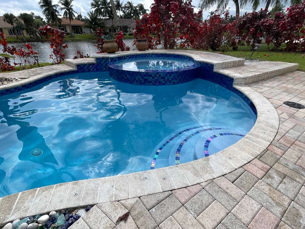 Waterfront pool resurfacing with spa and decorative tile work